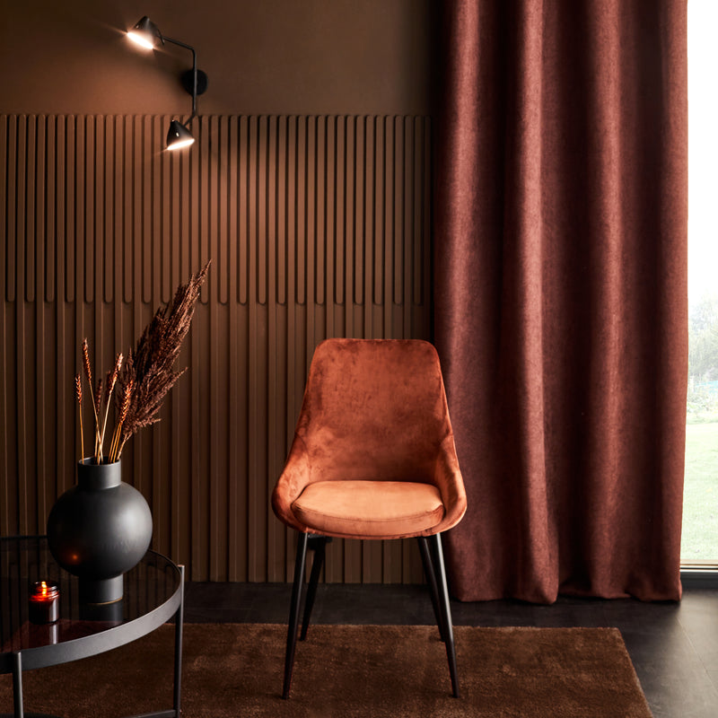 Mur brunaux reliefs verticaux dans pièce décorée d'une chaise et textiles bruns