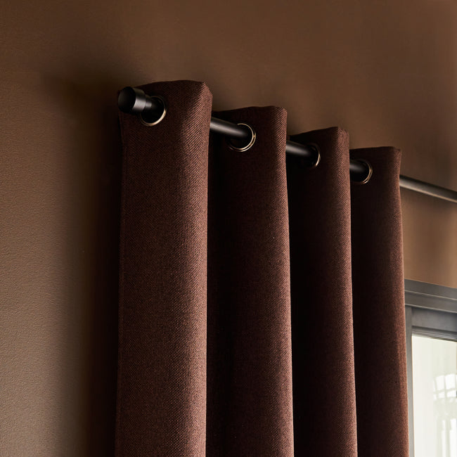 Photo plan serré sur le haut d'un rideau thermique marron sur barre à rideau fixée