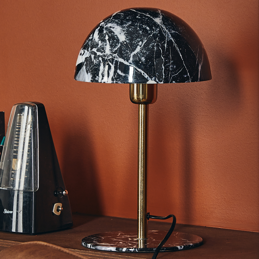 Lampe champignon à motif marbré noir et blanc devant un mur terracotta