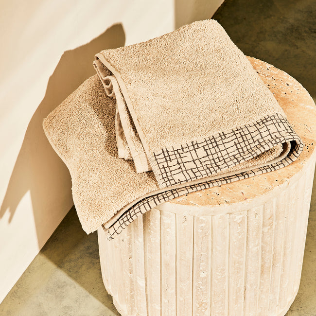 serviette de bain beige posée sur un tabouret