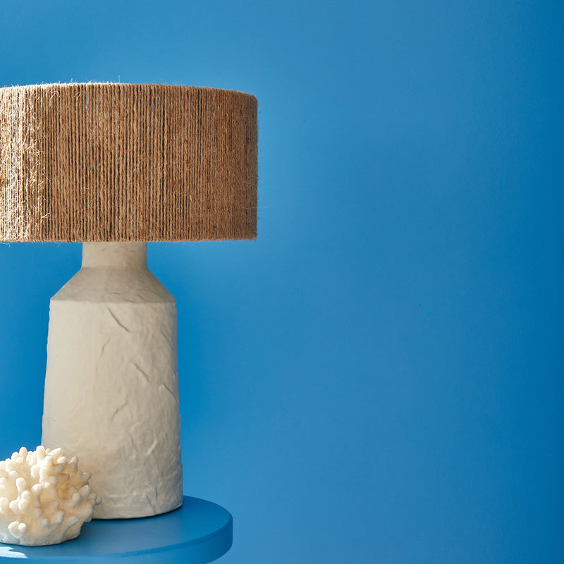 Lampe à poser blanche et jute devant mur bleu médina