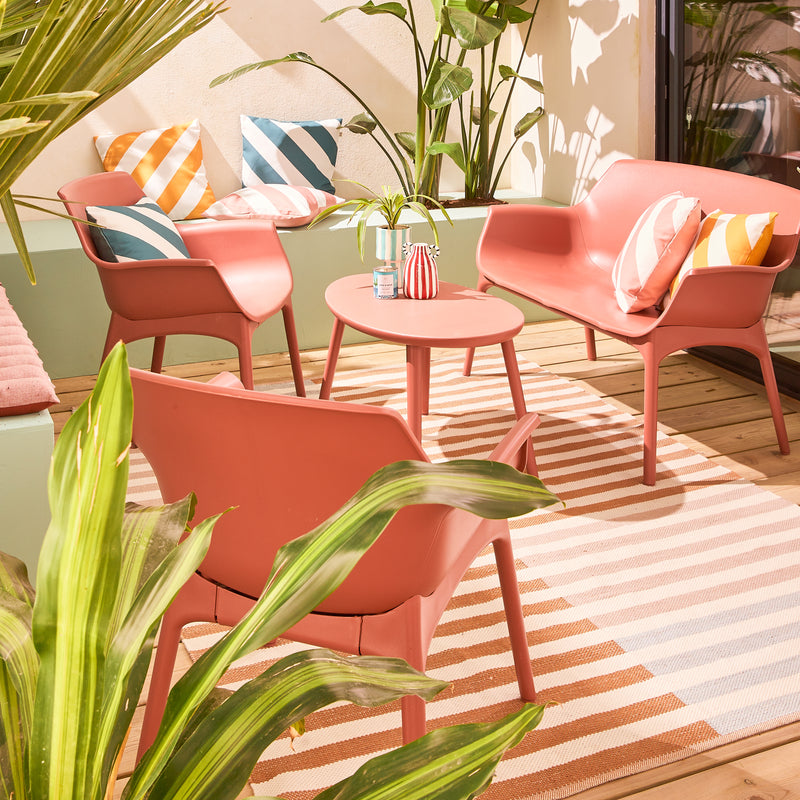 Salon de jardin terracotta avec coussins et tapis rayés