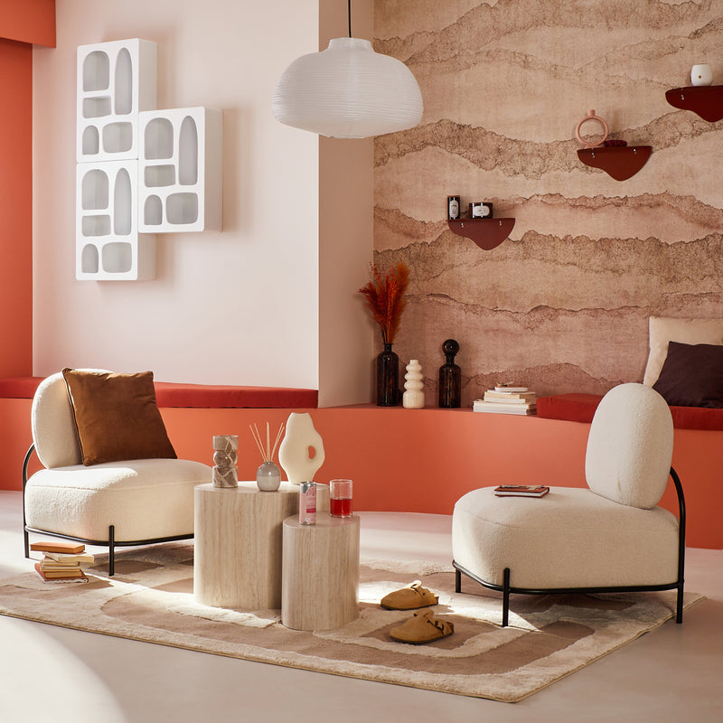 Salon aux tons terracotta et beige avec deux fauteuils arrondis crème