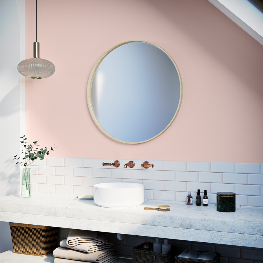 Salle de bain mur rose pastel et carrelage blanc avec miroir rond