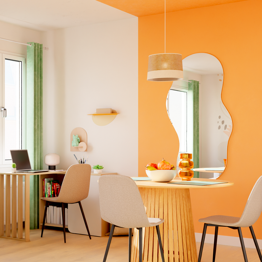 Coin repas délimité par mur orange avec coin bureau adjacent