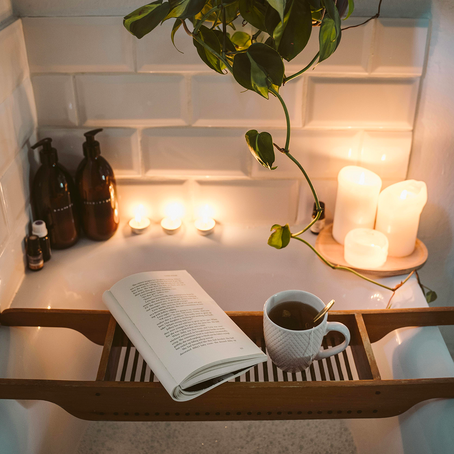 Ambiance bain moussant avec bougies, livre et tasse de thé