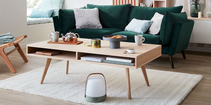 Déco salon style scandinave, canapé velours vert foncé, table basse en bois clair, tapis beige moelleux