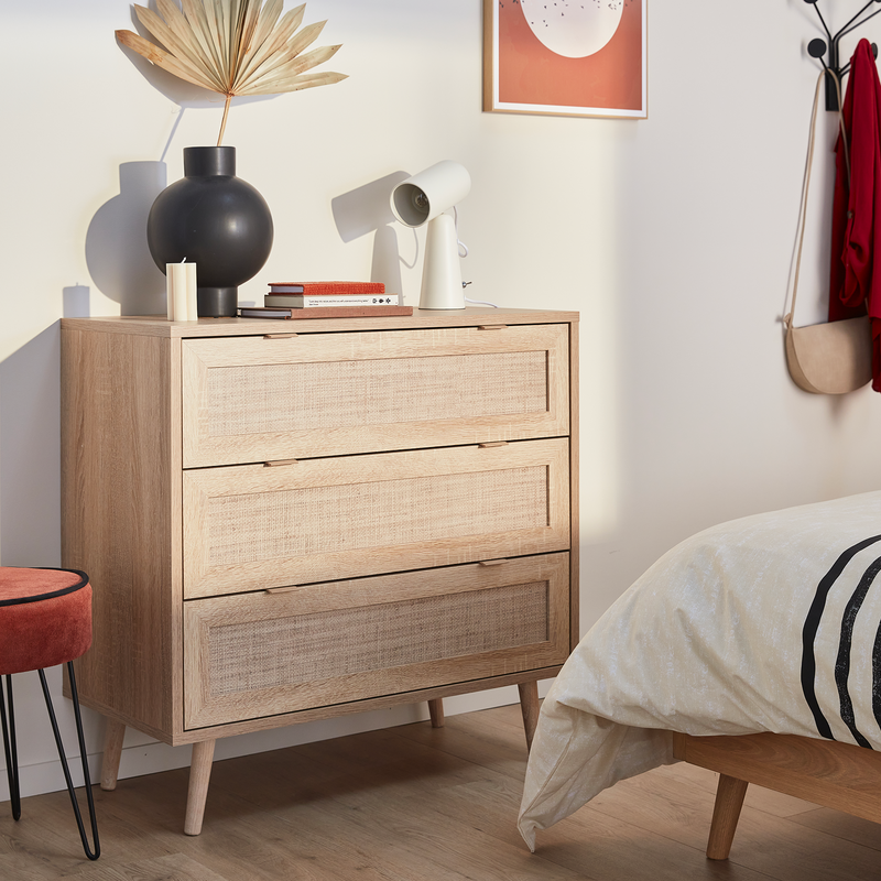 Commande en bois clair et rotin avec vase noir et lampe à poser dans chambre