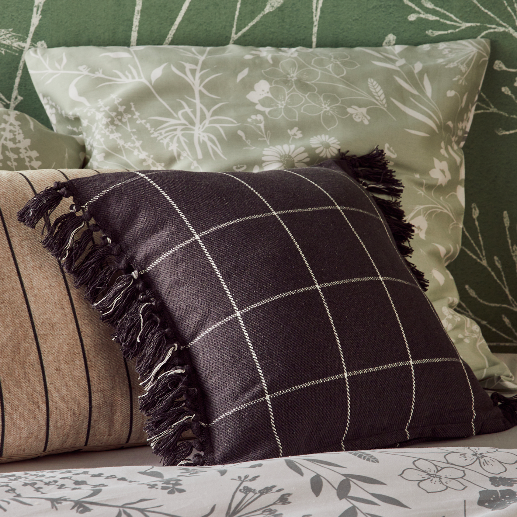 Coussin noir à grands carreaux posé sur un lit 