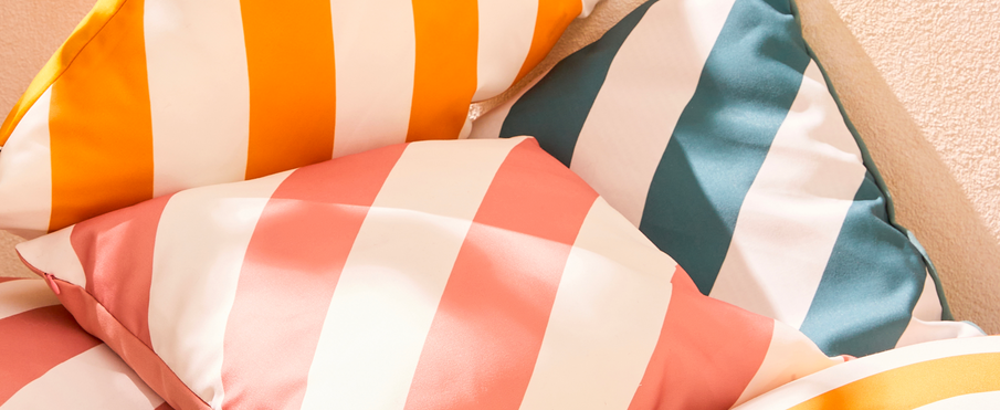Zoom sur trois coussins à rayures orange, rose et bleu