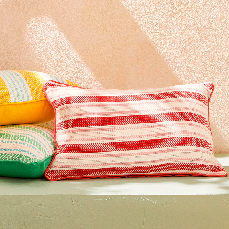 Coussins à rayures bayadères rouges, jaunes et verts sur une banquette