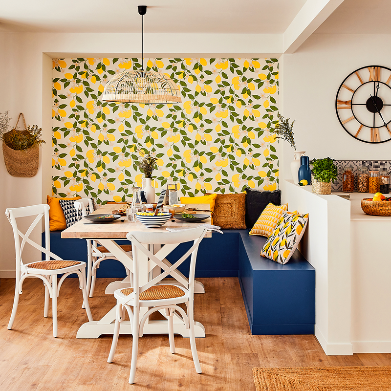 Coin repas avec mobilier blanc et banquette bleue devant papier peint motif citrons