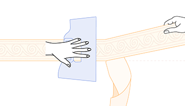 Main tenant une spatule à maroufler pour poser une frise adhésive au mur