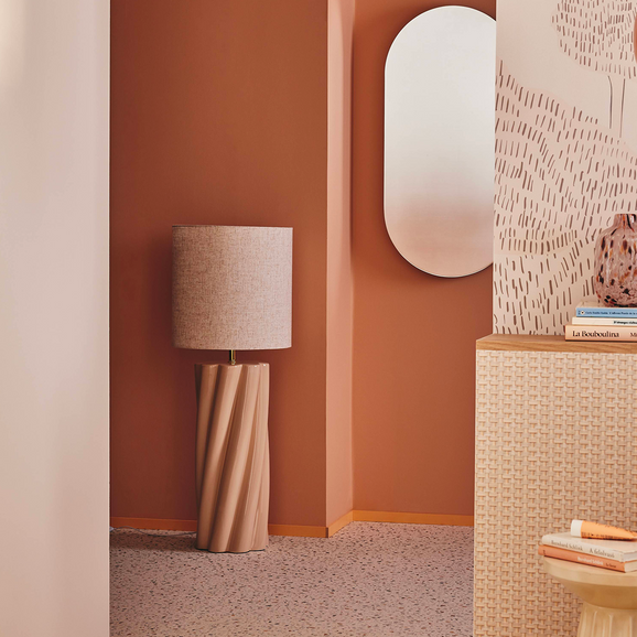 Lampadaire beige au pied torsadé, papier peint au mur couleur abricot