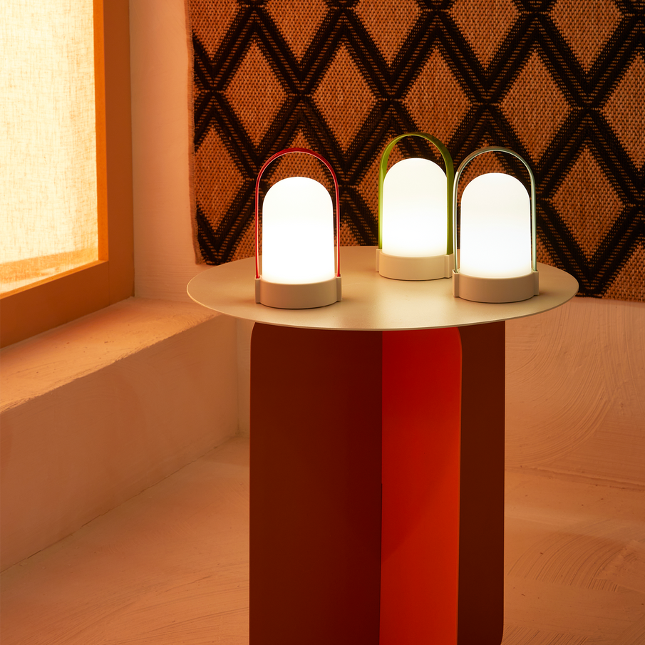  3 lampes d'extérieur allumées posées sur une table d'appoint