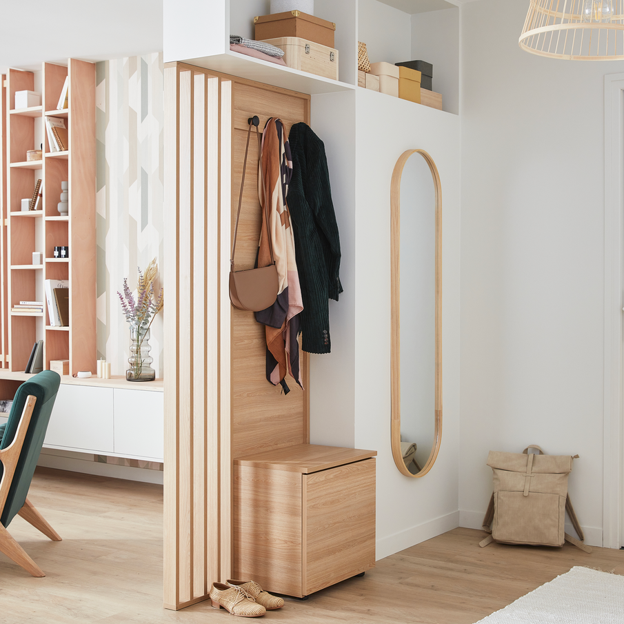 Grand meuble en bois clair qui sert de porte manteaux dans une entrée aux murs blancs