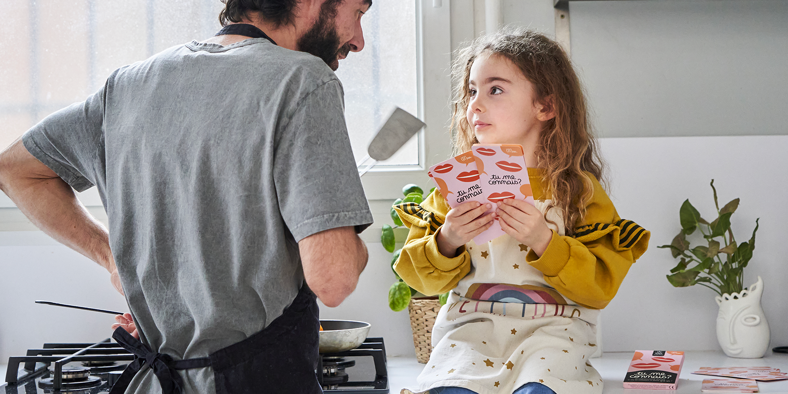 Une enfant et un homme jouant au jeu de cartes Tu me connais ? de la marque Minus éditions