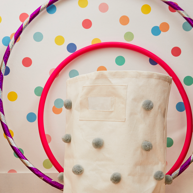 Cerceaux et panier posés contre un papier peint blanc à points multicolores