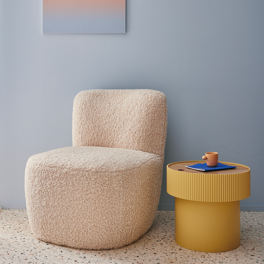 Fauteuil de laine bouclé devant un mur bleu ciel