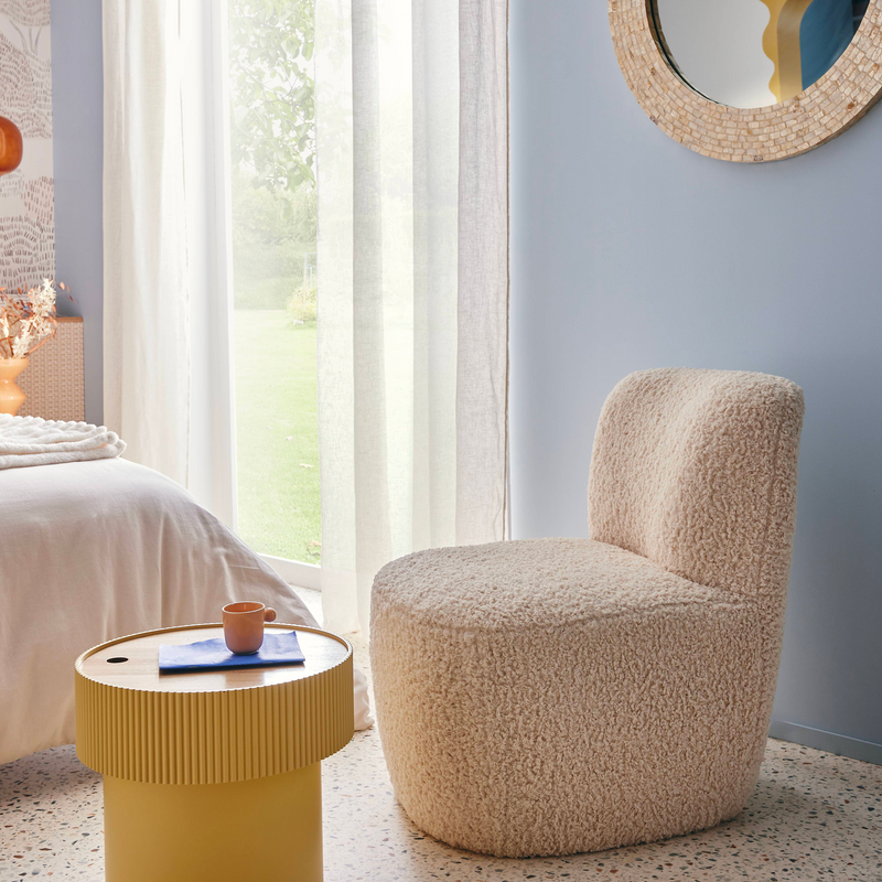 Fauteuil rond au tissu bouclette blanc dans une chambre aux couleurs pastel