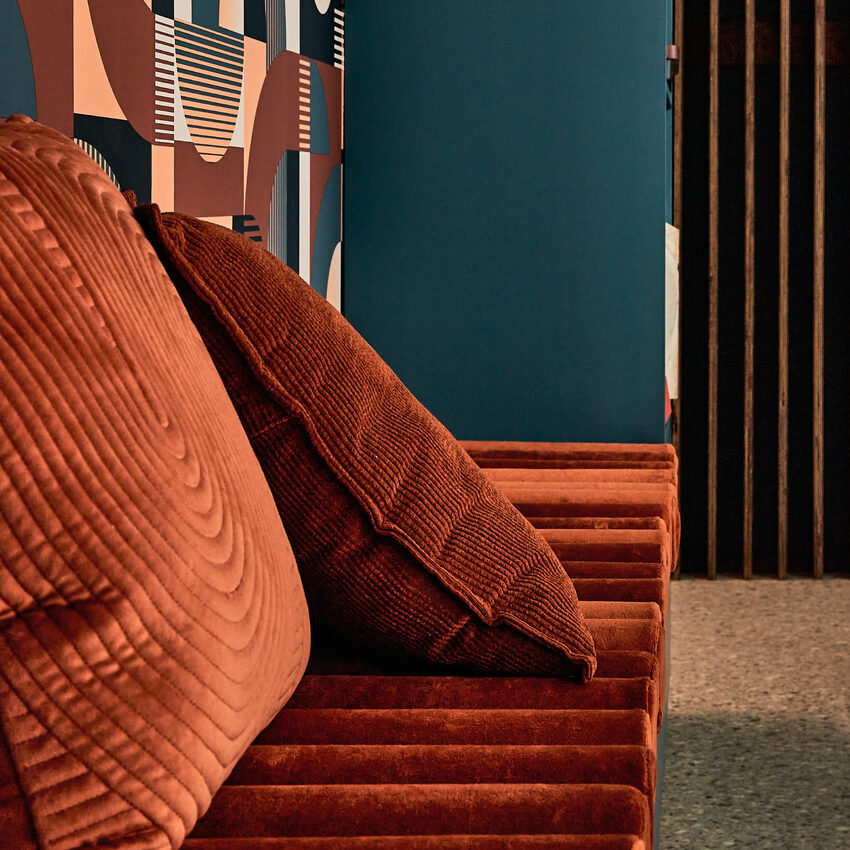 Focus sur des coussins couleur cognac sur mur bleu