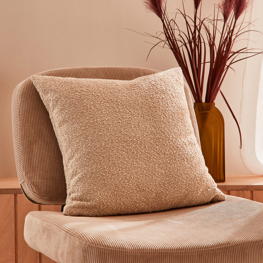 Coussin bouclette beige sur fauteuil en velours